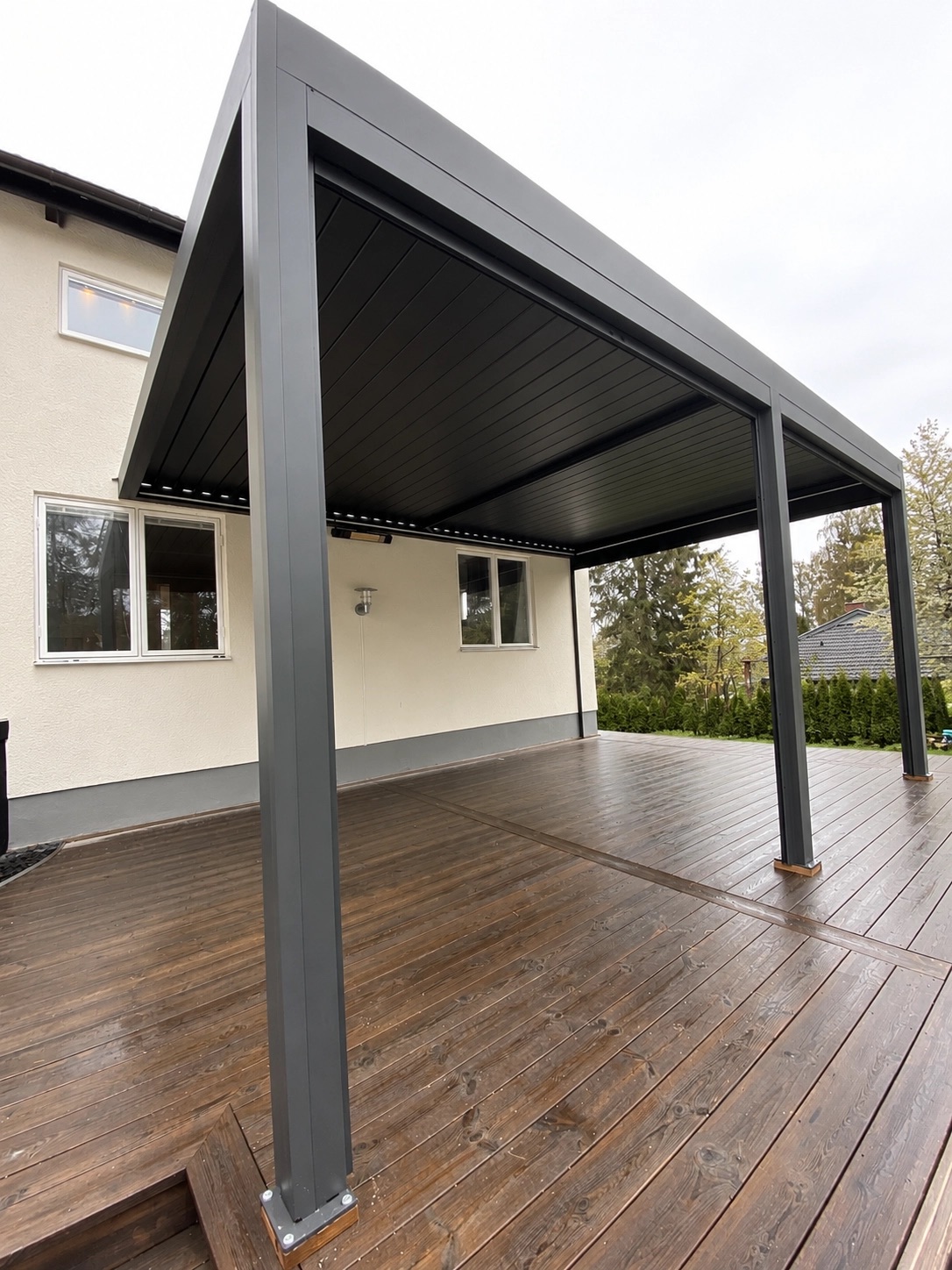 Stor mörkgrå PERGOLUX pergola monterad på rymlig träaltan